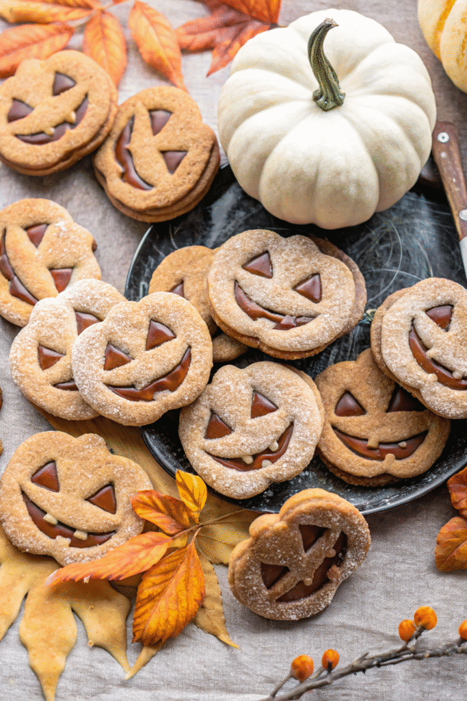 Milk chocolate stuffed jack-o'-lantern cookies stacked on a wooden table.