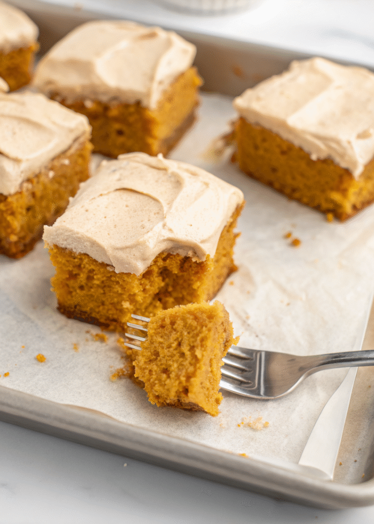 Sliced pumpkin spice cake with cinnamon cream cheese frosting on rustic wooden board